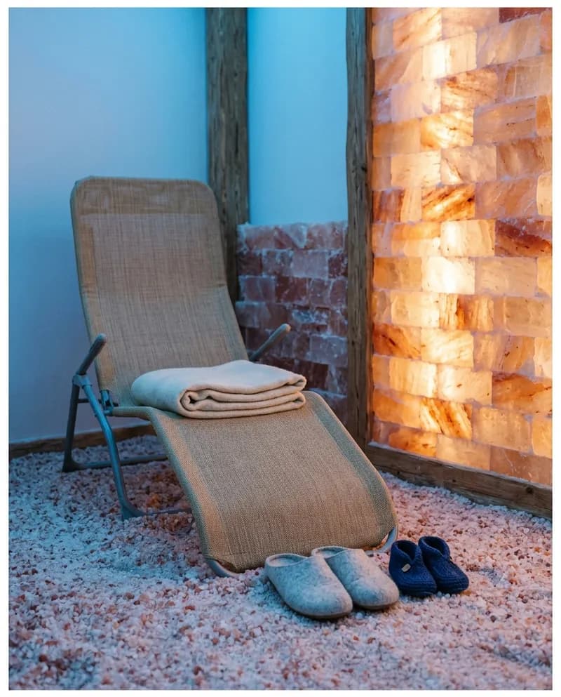 Cadeiras reclináveis numa sala com paredes de blocos de sal rosa e luz colorida suave